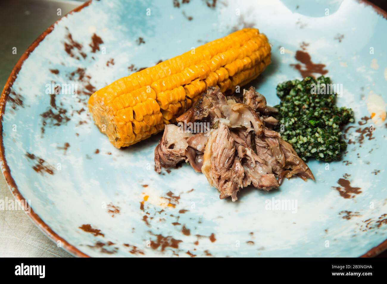 Sulla costata di mais e salsa verde viene servita della carne succosa preparata di fresco. Il cibo si trova su una piastra rotonda. Pronto a servire. Foto Stock