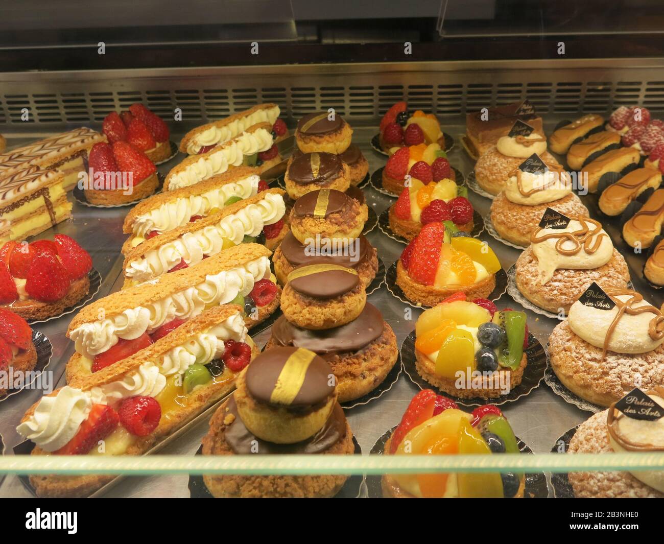 Un vassoio di succulenti leclairs crema, crostate e pasta choux, in vendita presso una pasticceria francese. Foto Stock