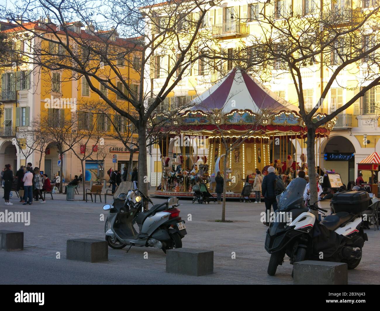 Vista di Place Garibaldi nel centro di Nizza, con giostra tradizionale,  moto parcheggiate e famiglie in gruppi in tutta la piazza Foto stock - Alamy