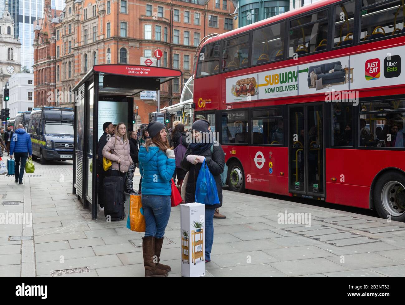 Fermata dell'autobus di Londra; fermata dell'autobus di Liverpool Street, Londra UK - persone e un autobus alla fermata dell'autobus di Liverpool Street, Londra EC2 UK Foto Stock