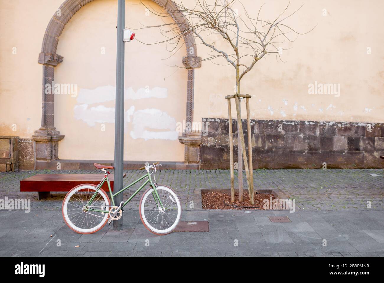 Vista sulla strada con la bicicletta retro parcheggiata vicino alla panchina della città vecchia Foto Stock