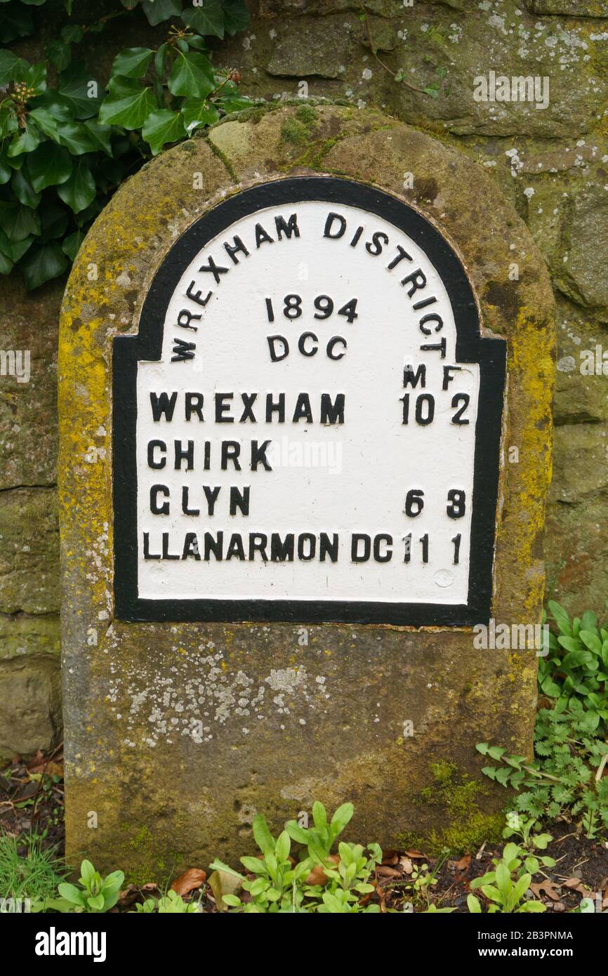 Vecchia pietra miliare dell'annata 1894 in ghisa che mostra le distanze da Wrexham Glyn Ceiriog e Llanarmon Dyffryn Ceiriog fuori dalla città di Chirk North Wales UK Foto Stock