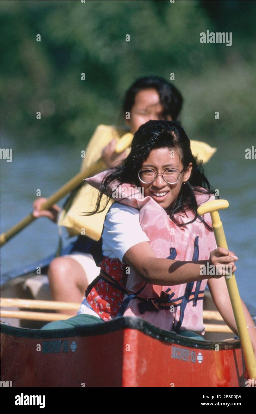 Bandera Texas USA, 1991: Ragazze di quinta classe che indossano conservatori di vita pagaia una canoa durante un viaggio di notte campo scuola ad un campo nel Texas Hill Country. ©Bob Daemmrich Foto Stock