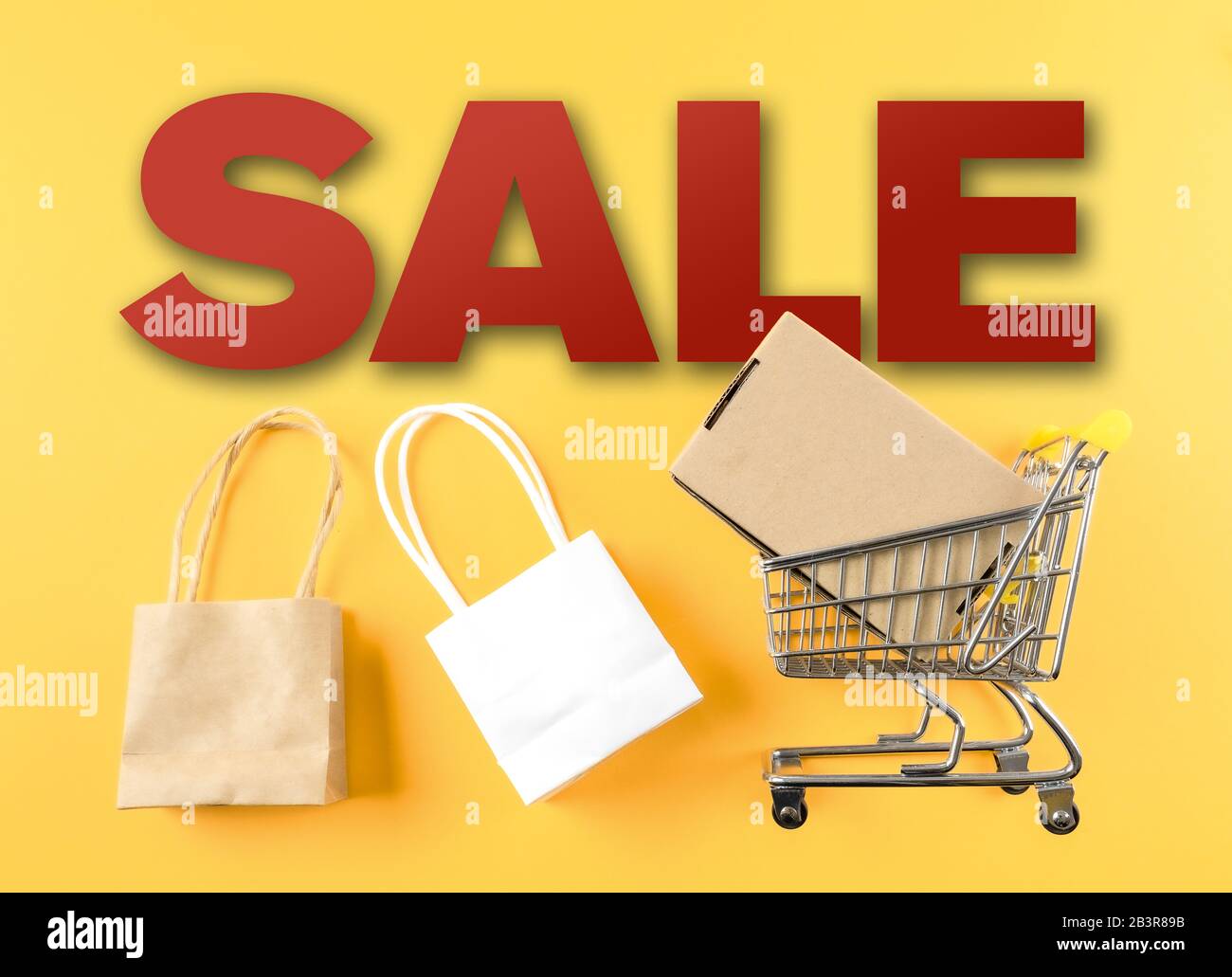 Vendita al dettaglio marketing concept con vendita di parola e carrello e borse su sfondo giallo Foto Stock