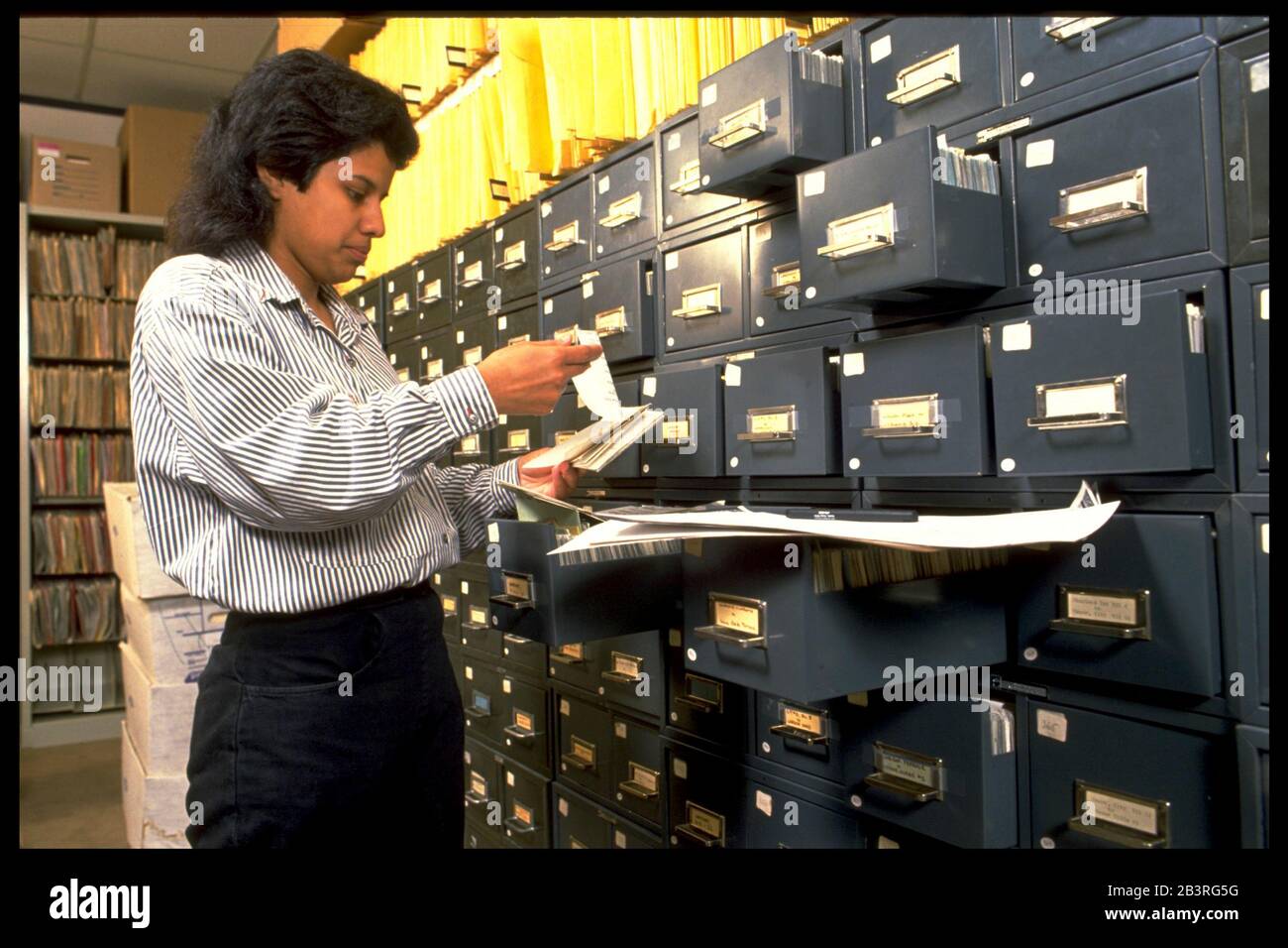 Austin Texas USA, circa 1992: L'impiegato di deposito ispanico cerca i file astratti della carta al commercio di assicurazione di titolo. ©Bob Daemmrich Foto Stock