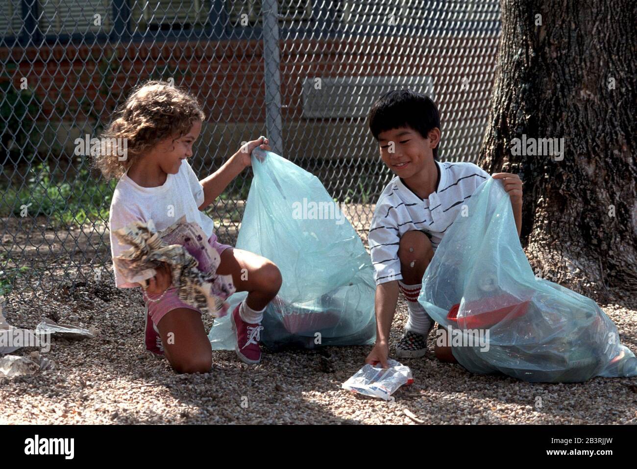 Austin Texas USA: Ragazzo e ragazza di otto e nove anni raccolse la lettiera nei campi della scuola. ©Bob Daemmrich Foto Stock