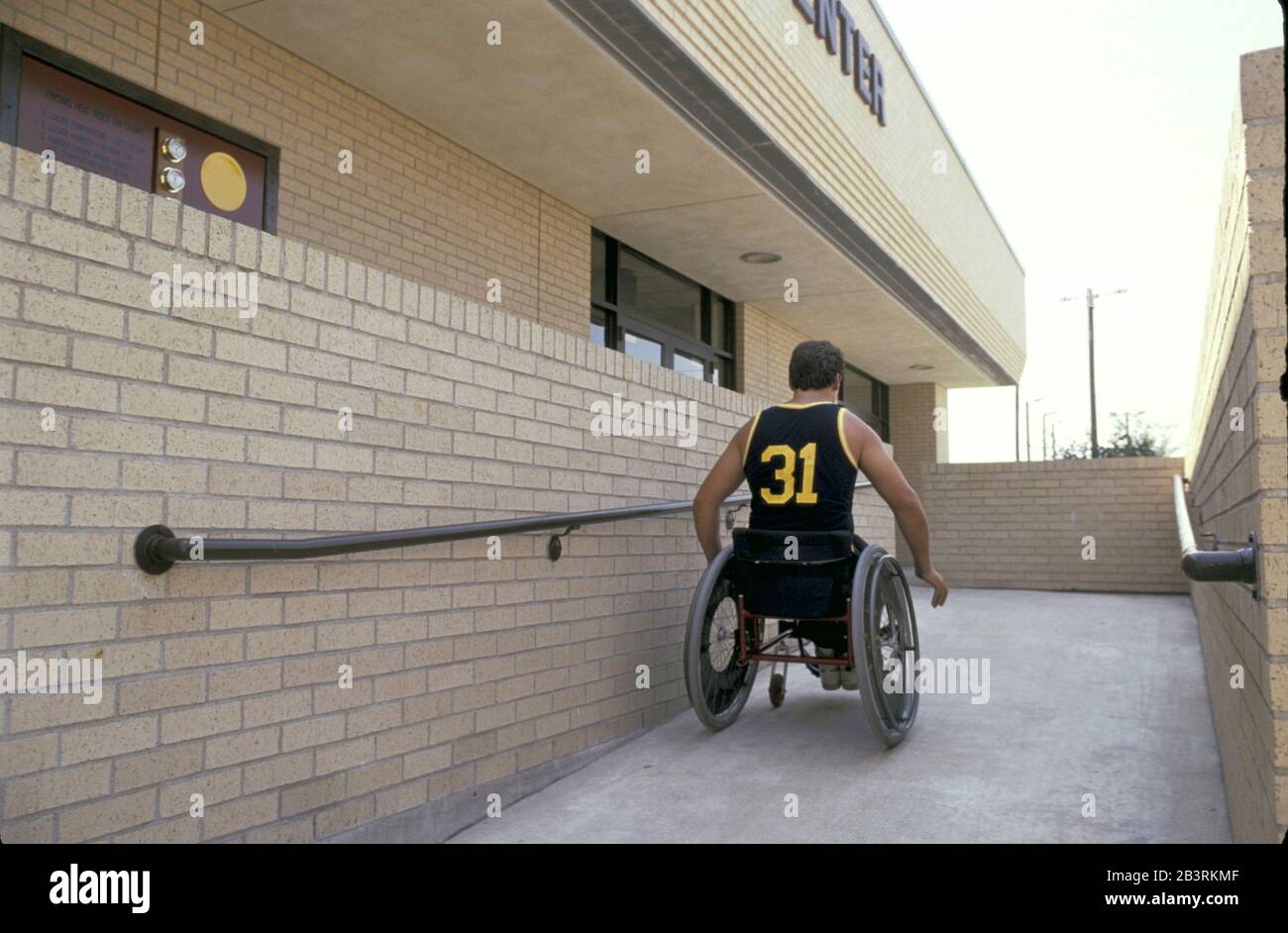 Austin Texas USA, circa 1991: L'atleta disabili utilizza una rampa per sedie a rotelle per entrare nel centro ricreativo pubblico. ©Bob Daemmrich Foto Stock