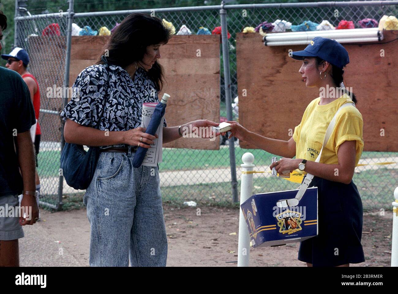 Austin Texas USA circa 1993: La giovane donna offre un pacchetto di sigarette in omaggio come promozione per il marchio Camel al festival della comunità ispanica. ©Bob Daemmrich Foto Stock