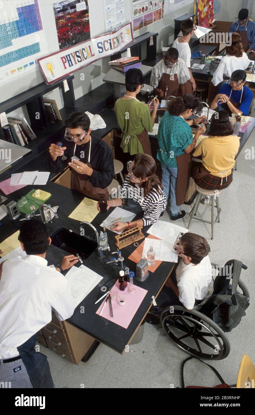 Austin, Texas USA, circa 1997: Il ragazzo handicappato in sedia a rotelle partecipa agli esperimenti di laboratorio con i compagni di classe durante la classe di biologia della scuola superiore. ©Bob Daemmrich Foto Stock