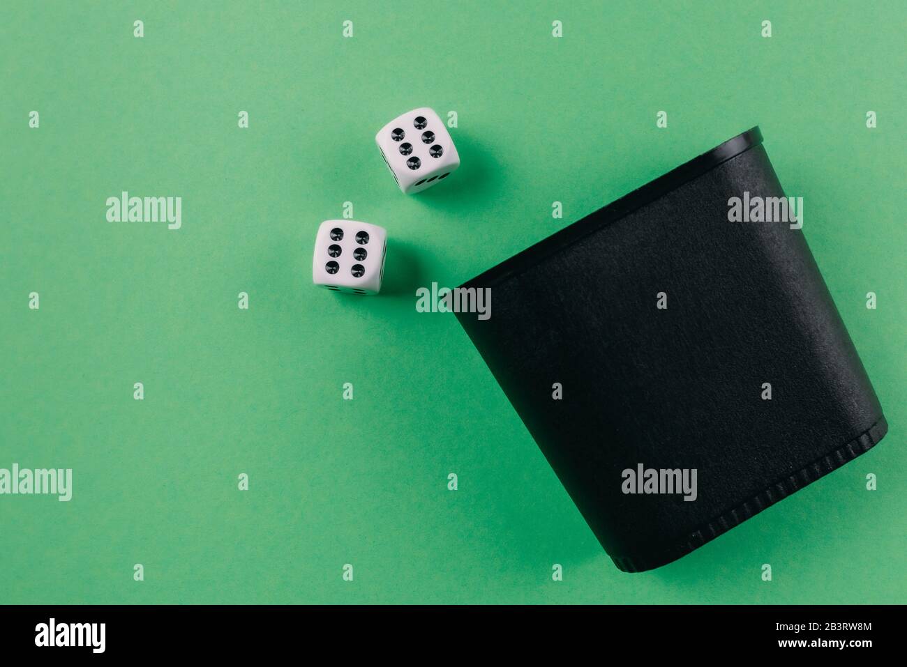 vista dall'alto dello shaker dei dadi e dei dadi sullo sfondo del tavolo da gioco verde Foto Stock