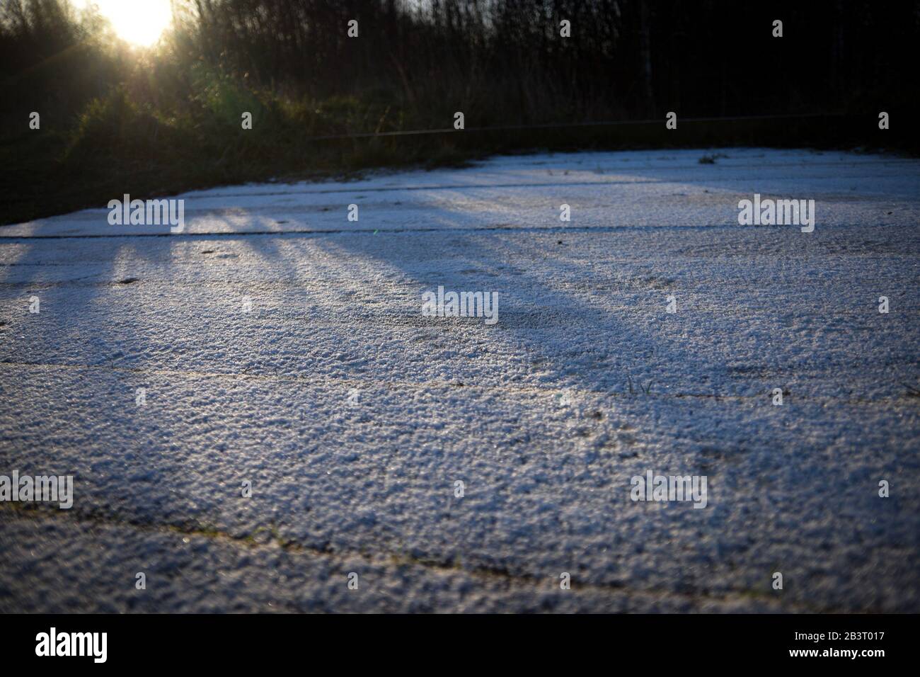 I primi raggi di sole gettano ombre su una copertura di luce della neve per mostrare le sue texture. Un grande inverno o Natale sfondo o concetto. Foto Stock