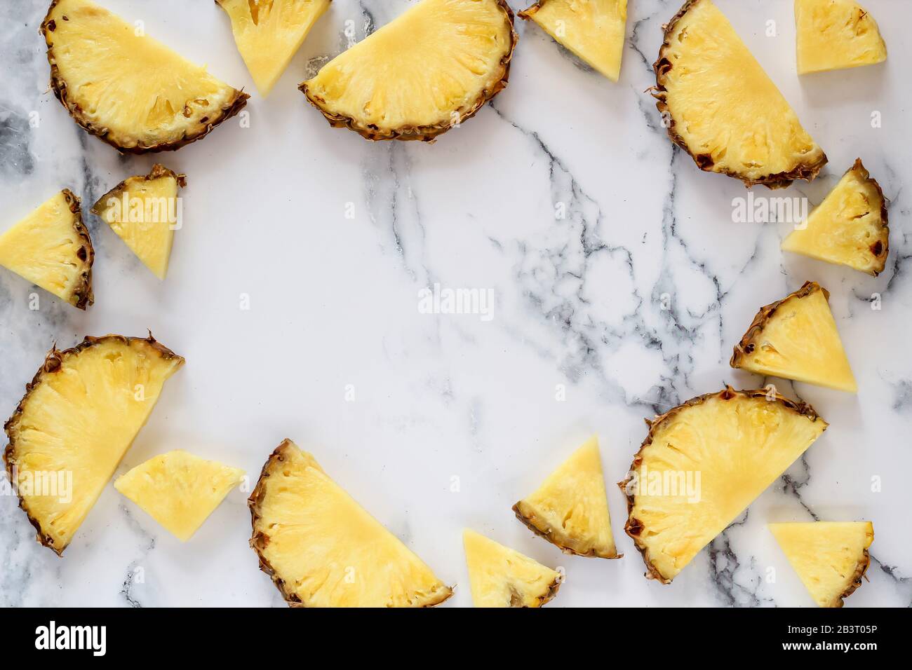 Fette di ananas su uno sfondo di marmo bianco con uno spazio copia al centro Foto Stock