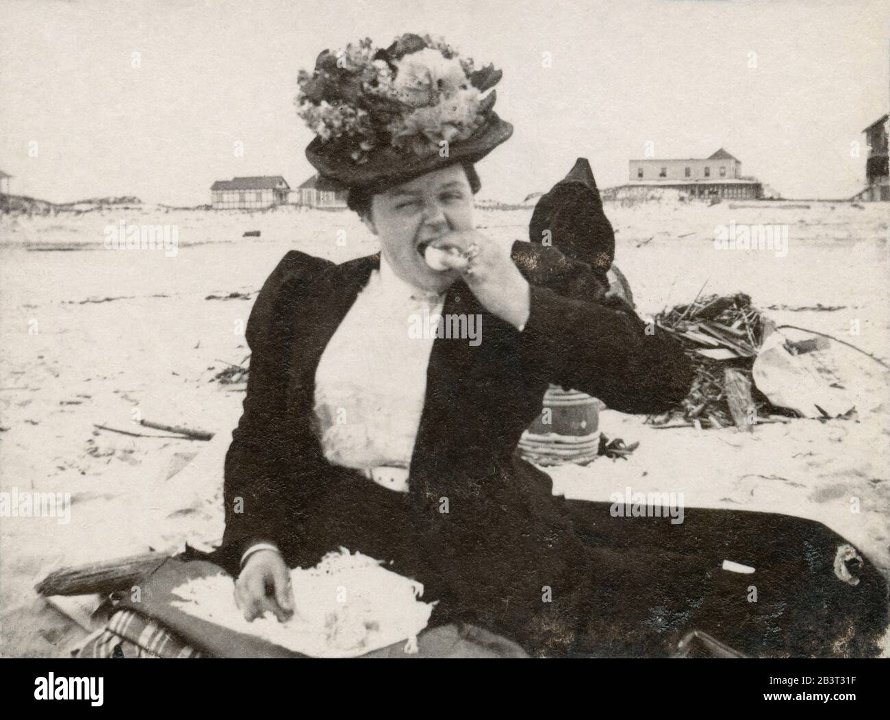 Fotografia del 1898 antico, donna vittoriana seduta sulla sabbia mangiare un uovo a Long Beach, New York. FONTE: FOTOGRAFIA ORIGINALE Foto Stock