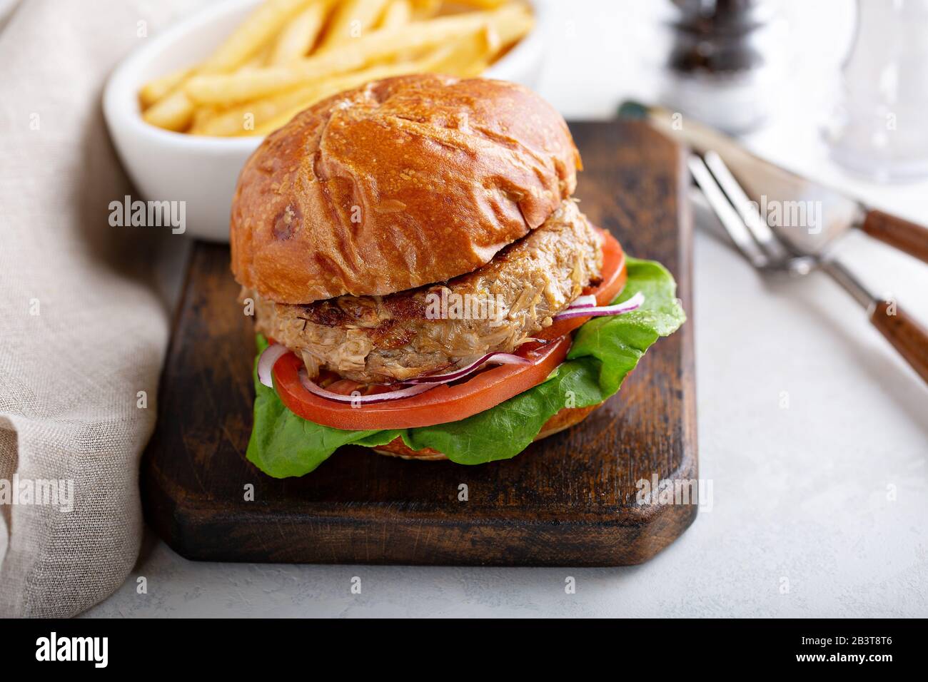 Hamburger vegano a base di piante con pomodoro e lattuga servito con patatine fritte Foto Stock