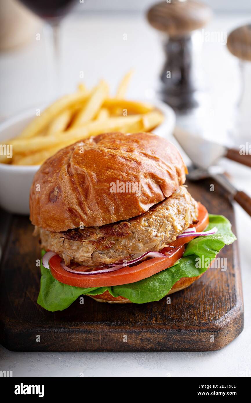 Hamburger vegano a base di piante con pomodoro e lattuga servito con patatine fritte Foto Stock