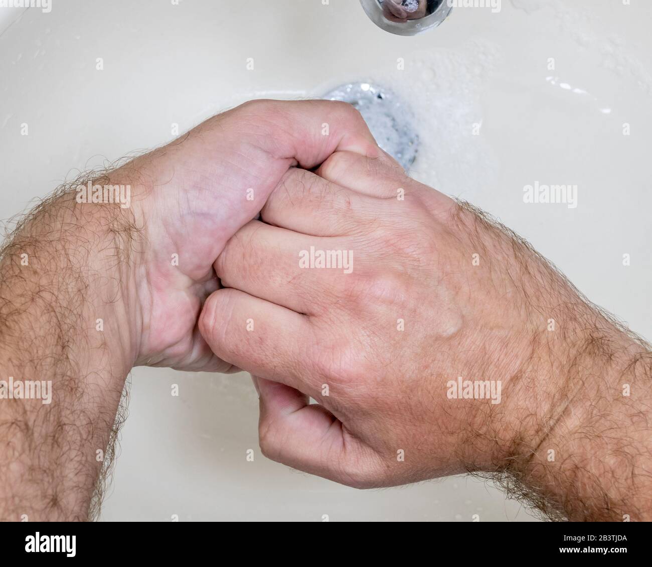 Uomo lavando le mani vicino-in su dall'alto, uno di parecchi punti di handwashing per la pulizia accurata Foto Stock
