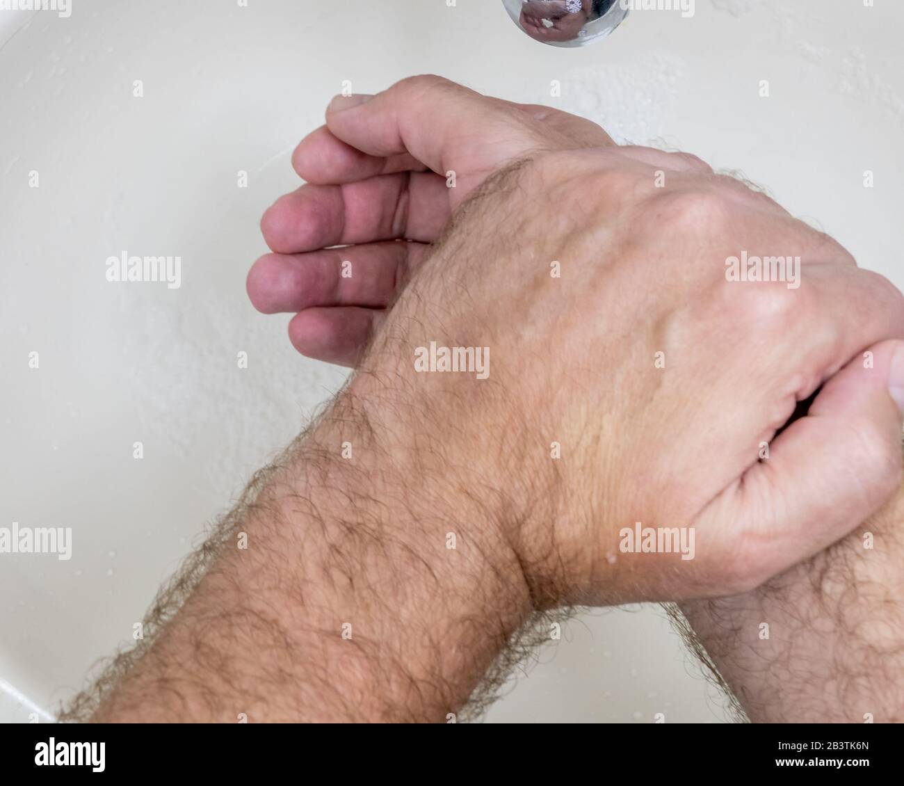 Uomo lavando le mani vicino-in su dall'alto, uno di parecchi punti di handwashing per la pulizia accurata Foto Stock