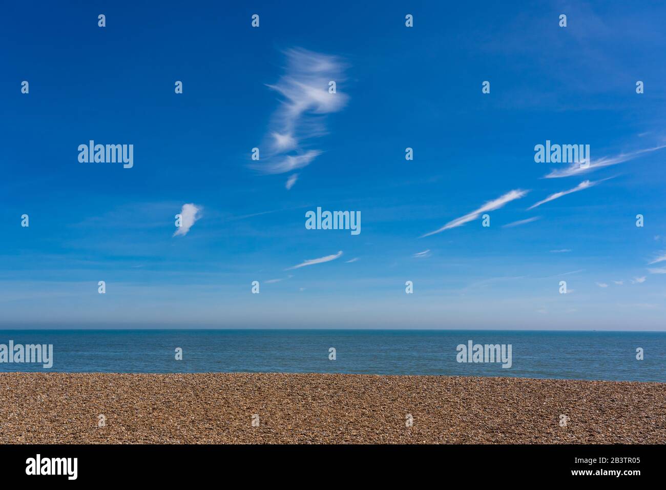 Spiaggia vuota che mostra cielo blu, mare e ghiaia. Aldeburgh. Suffolk. REGNO UNITO Foto Stock