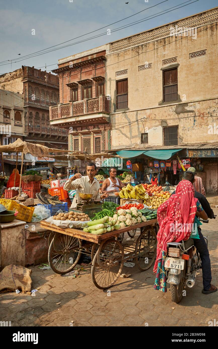 Gente colorata vestita alla stalla di mercato con frutta e verdure a Bikaner, Rajasthan, India Foto Stock