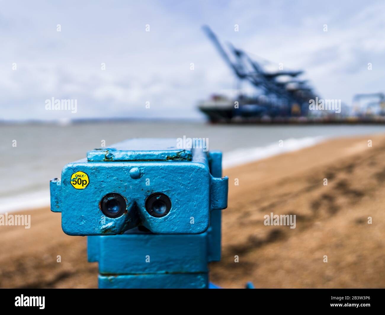 Una vista sul commercio internazionale - UNO sguardo al commercio - un telescopio di spiaggia punti alle navi scaricate al porto di Felixstowe. Foto Stock