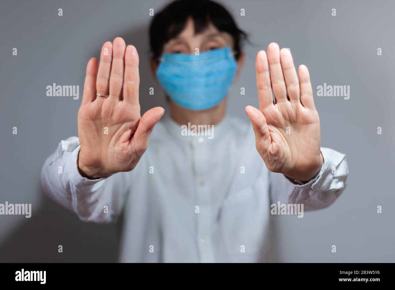 Arrestare la quarantena del coronavirus e il concetto di inquinamento atmosferico pm2.5. Donna anziana malata che indossa maschera respiratore per proteggere con braccio allungato. Wuhan, Cina ep Foto Stock