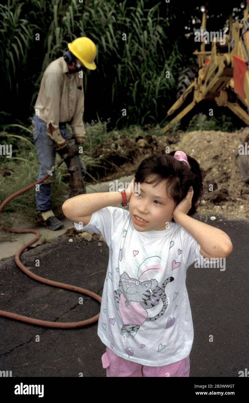 Austin Texas USA: La giovane ragazza ispanica copre le orecchie per bloccare il rumore forte del martello pneumatico. ©Bob Daemmrich Foto Stock