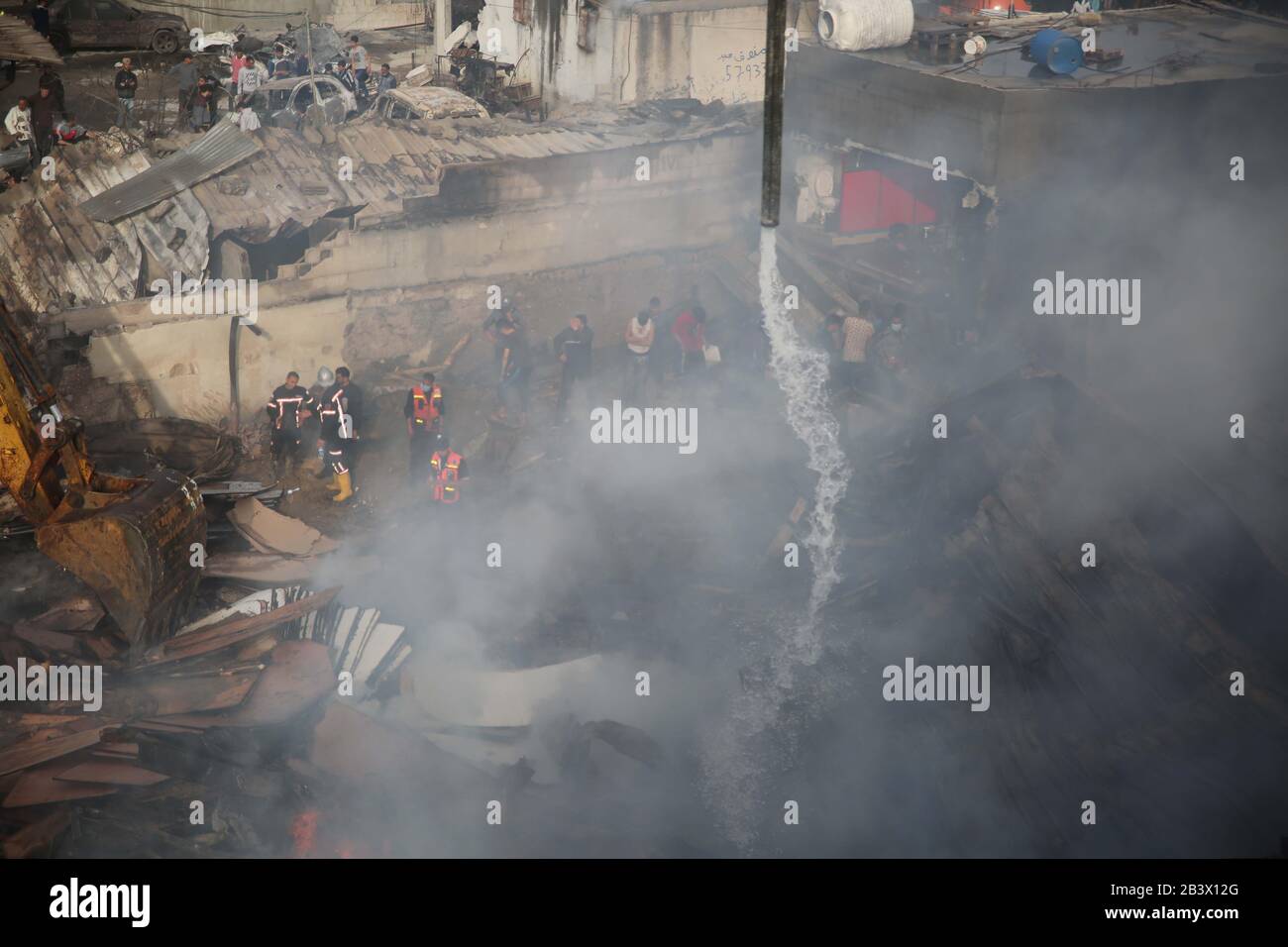 I palestinesi si riuniscono sulla scena di un incendio scoppiato in un mercato nel campo profughi di Nuseirat nella striscia centrale di Gaza, il 5 marzo 2020. Foto Stock