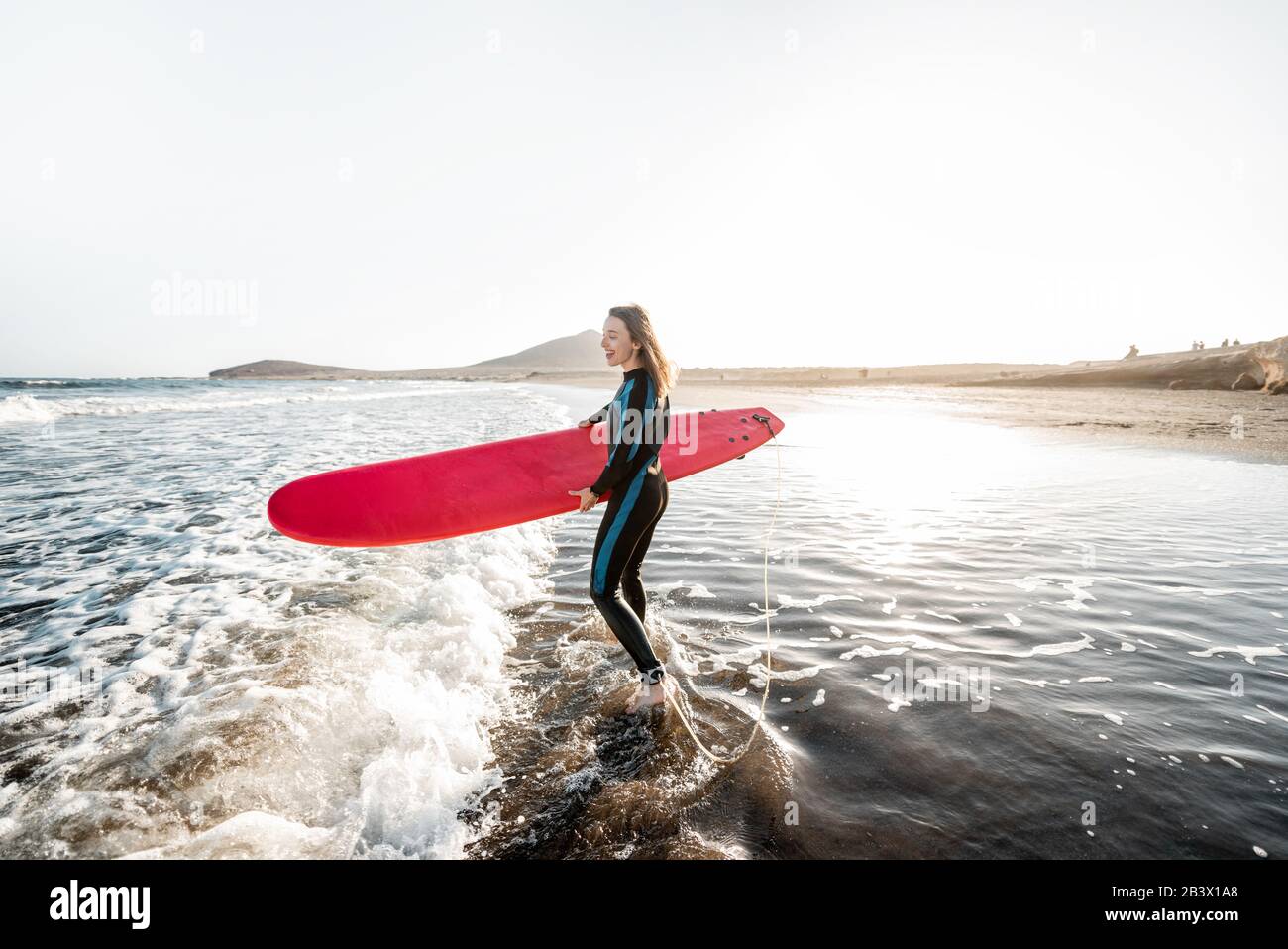 Giovane surfista in muta correndo con tavola da surf al mare. Attività estive e concetto di stile di vita attivo Foto Stock