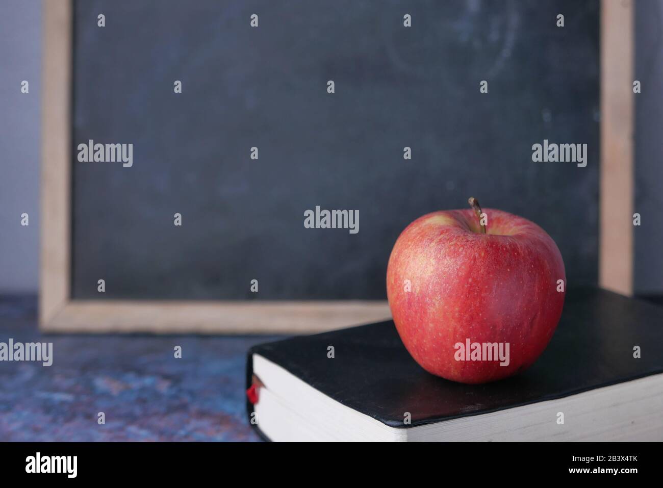 apple su un libro contro la lavagna nera, torna a scuola Foto Stock