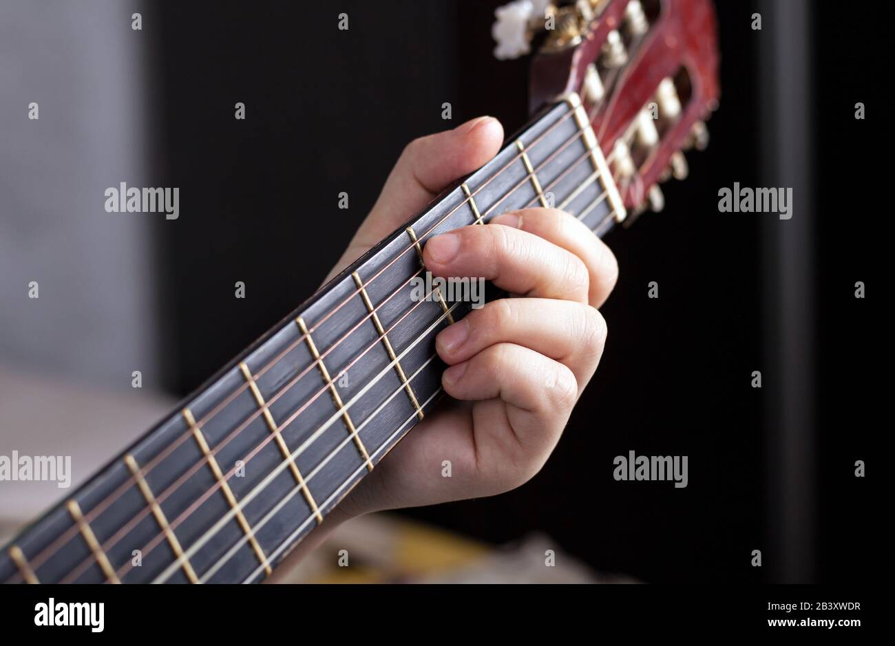 la mano del chitarrista stringe le dita sugli accordi di una chitarra  acustica Foto stock - Alamy