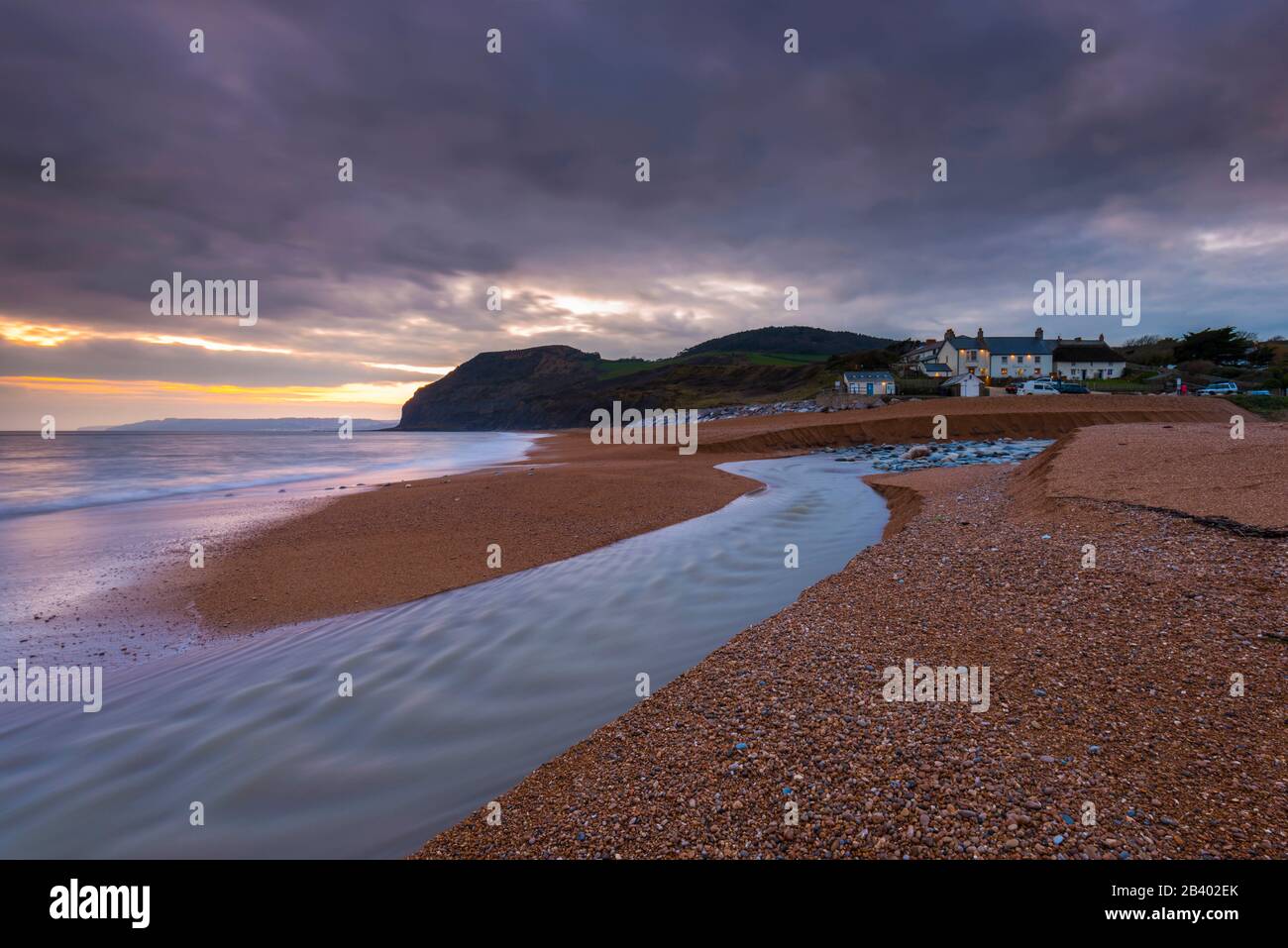 Seatown, Dorset, Regno Unito. 5th marzo 2020. Meteo Regno Unito. Vista della spiaggia di Seatown a Dorset poco dopo il tramonto dopo una giornata di pioggia intensa con il fiume Winniford che scorre attraverso la spiaggia e in lontananza è la caratteristica scogliera a forma di Golden Cap, che è la scogliera più alta sulla costa meridionale dell'Inghilterra. Accanto alla spiaggia si trova l'Anchor Inn. Foto Di Credito: Graham Hunt/Alamy Live News Foto Stock