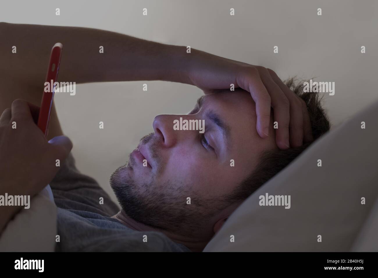 Dipendenza, nomofobia, insonnia, concetto di disturbo del sonno. Uomo addicted allo smartphone connesso 24 ore su 24, 7 giorni su 7 a Internet, sdraiato a letto e utilizzando smart phon Foto Stock