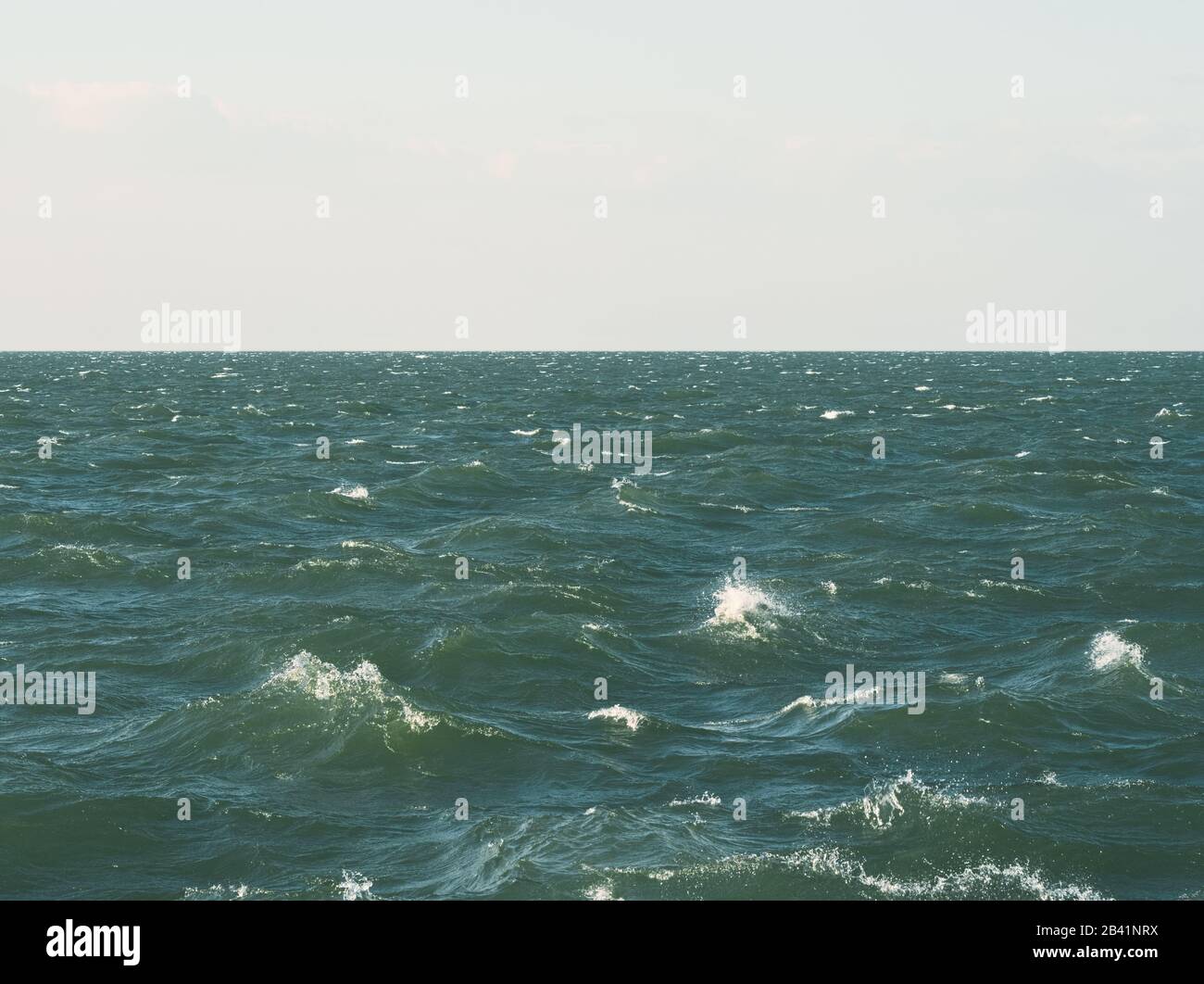 Superficie D'Acqua verdastra con Onde Stormy e orizzonte con cielo nuvoloso Foto Stock