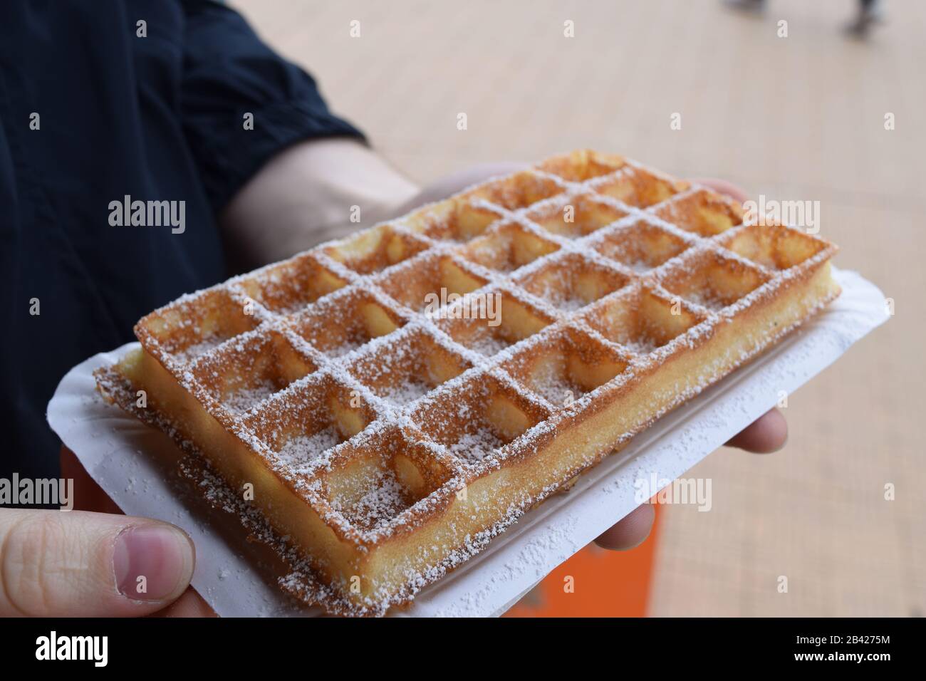 Primo piano di un cialda belga con zucchero a velo. Tourist in Belgio con un autentico waffle Foto Stock