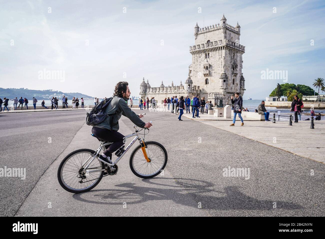 Un ciclista in bicicletta presso la famosa torre Belem, punto di riferimento di Lisbona, durante il giorno Foto Stock