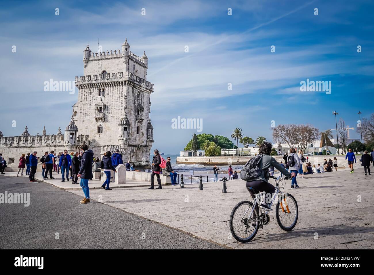 Un ciclista in bicicletta presso la famosa torre Belem, punto di riferimento di Lisbona, durante il giorno Foto Stock