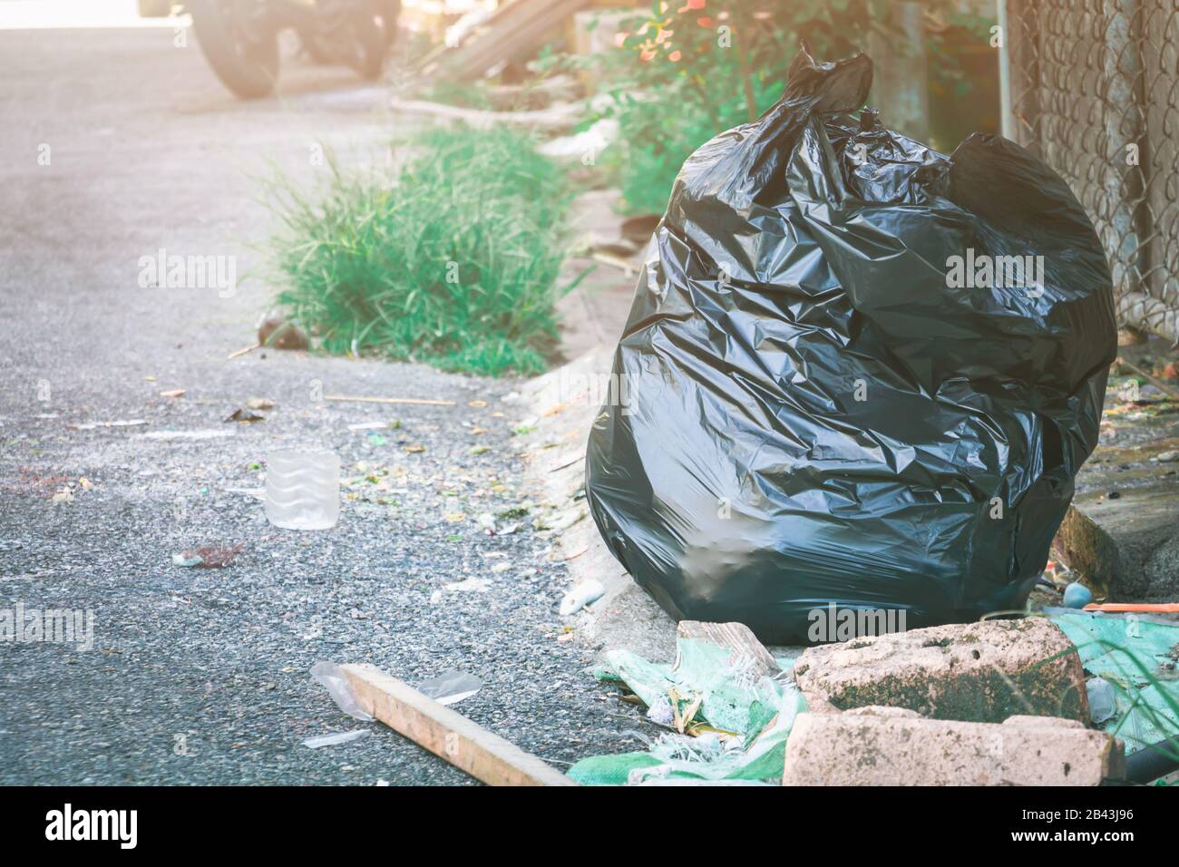 sacchetto di plastica per rifiuti. Palo nero su strada spazzatura Foto Stock