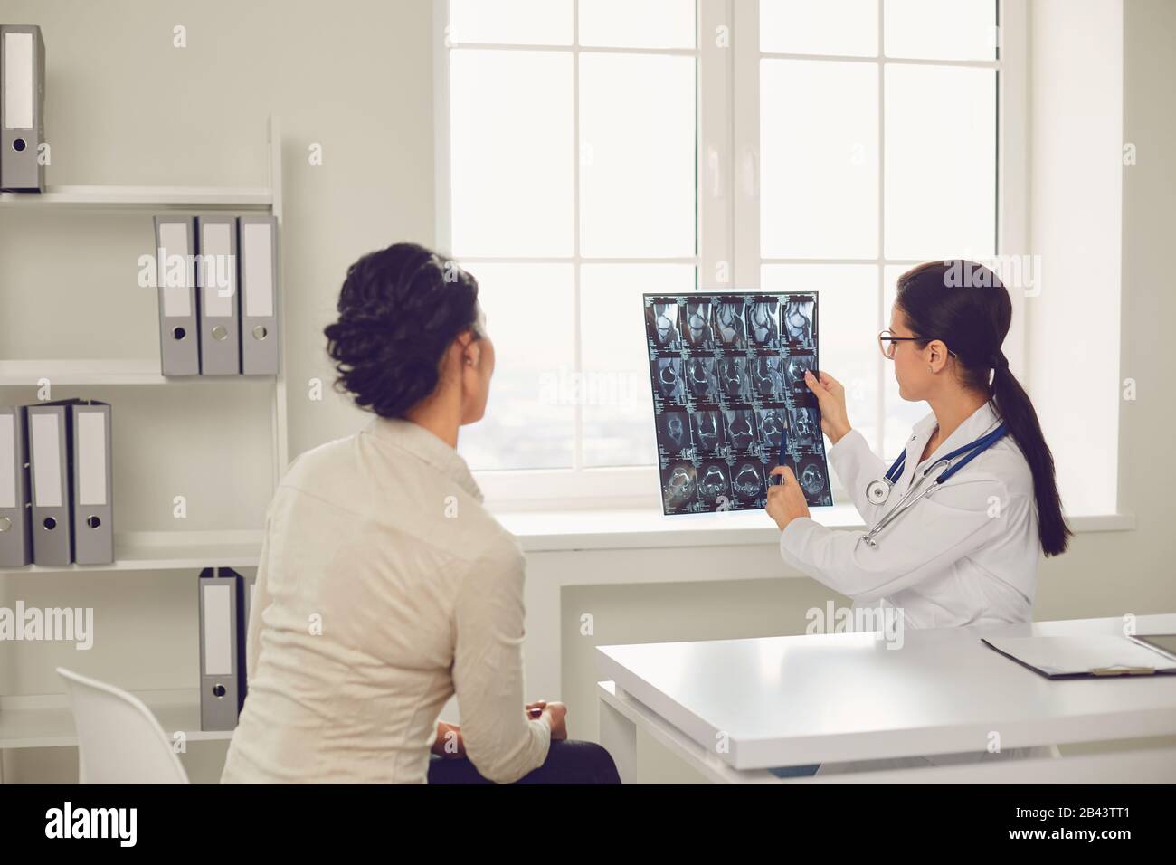 Medico donna con radiologia che parla cliente seduto a un tavolo in un ufficio clinica. Foto Stock