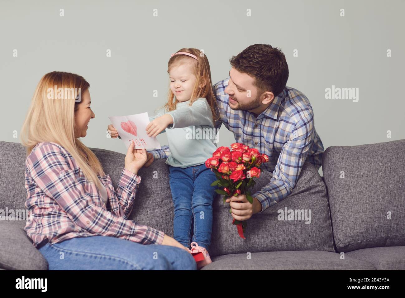 Buon giorno della madre. I bambini e il padre si congratulano con la mamma con i fiori dono Foto Stock