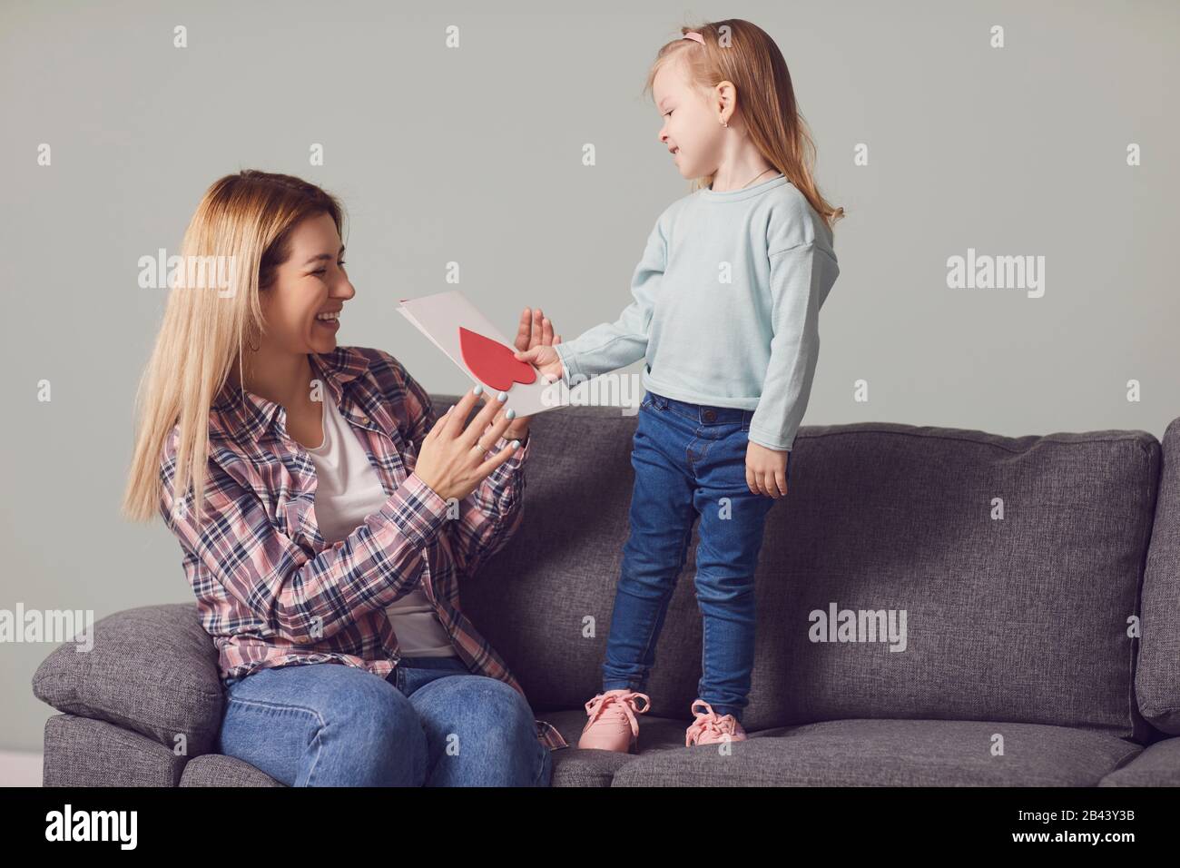 Buon giorno della madre. Figlia dà a mamma una carta con fiori cuore dono Foto Stock