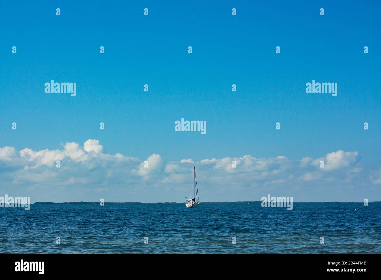 Barca a vela navigare attraverso l'oceano in un cielo nuvoloso chiaro. Foto Stock
