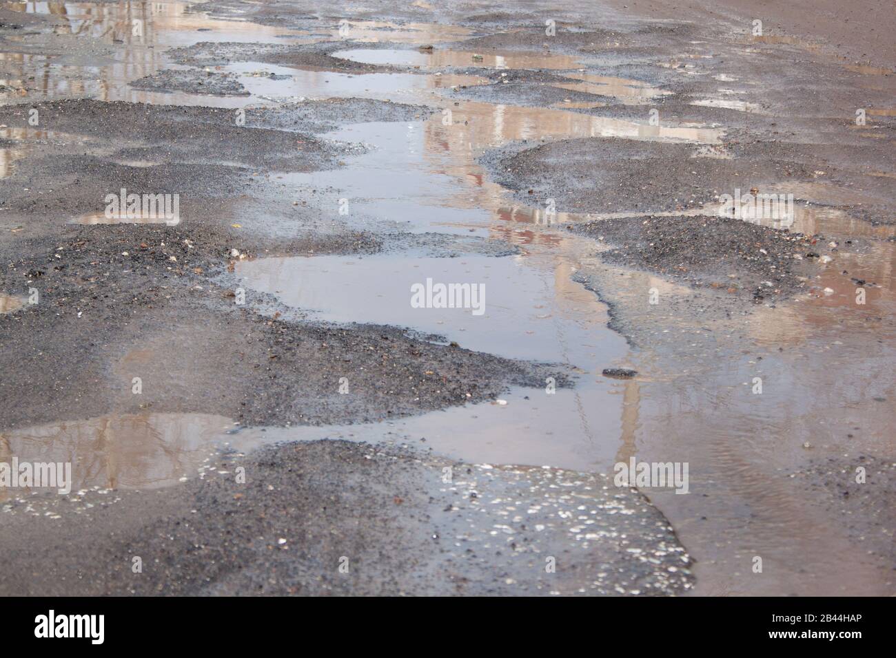 Pericoloso distrutto massicciata. La cattiva strada asfaltata. Grande buca riempita con acqua. Foto Stock