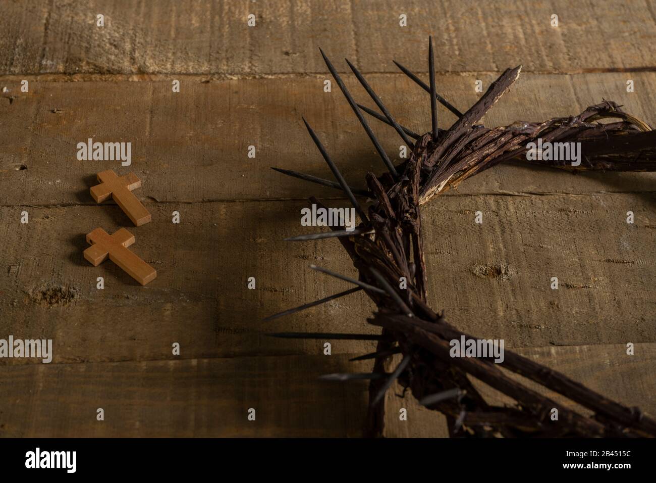 Primo piano di due piccole croci lignee e rappresentazione della corona di spine di Gesù Cristo su una superficie lignea Foto Stock