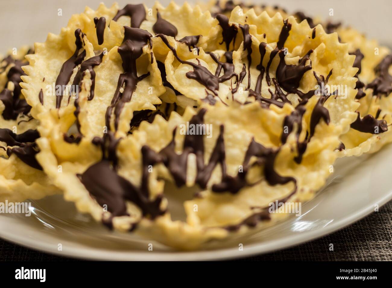 Bugie con cioccolato, un tradizionale frittelle carnevale italiano su piatto bianco Foto Stock