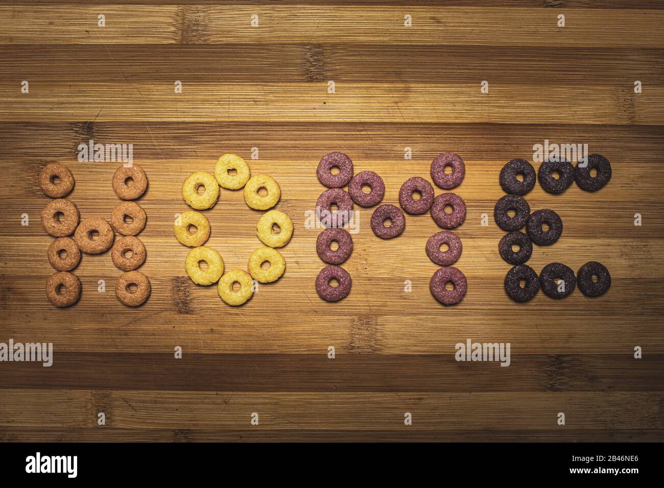 Questa scena è caratterizzata da cereali a forma di ciambella arancione, giallo, viola e rosa ortografia la parola Home in lingua inglese. Foto Stock