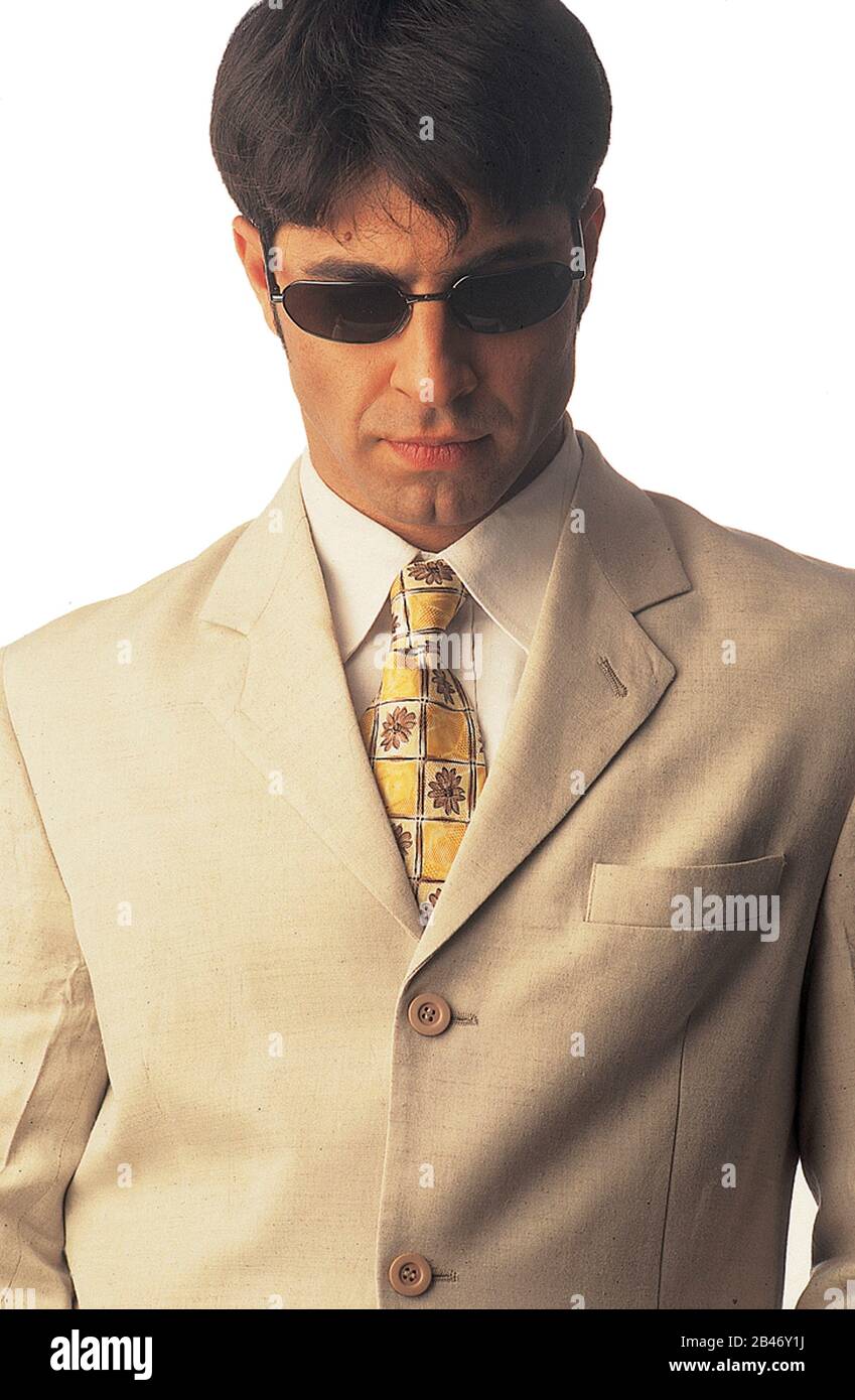 Uomo d'affari in giacca beige, camicia bianca, cravatta stampata e occhiali scuri Foto Stock