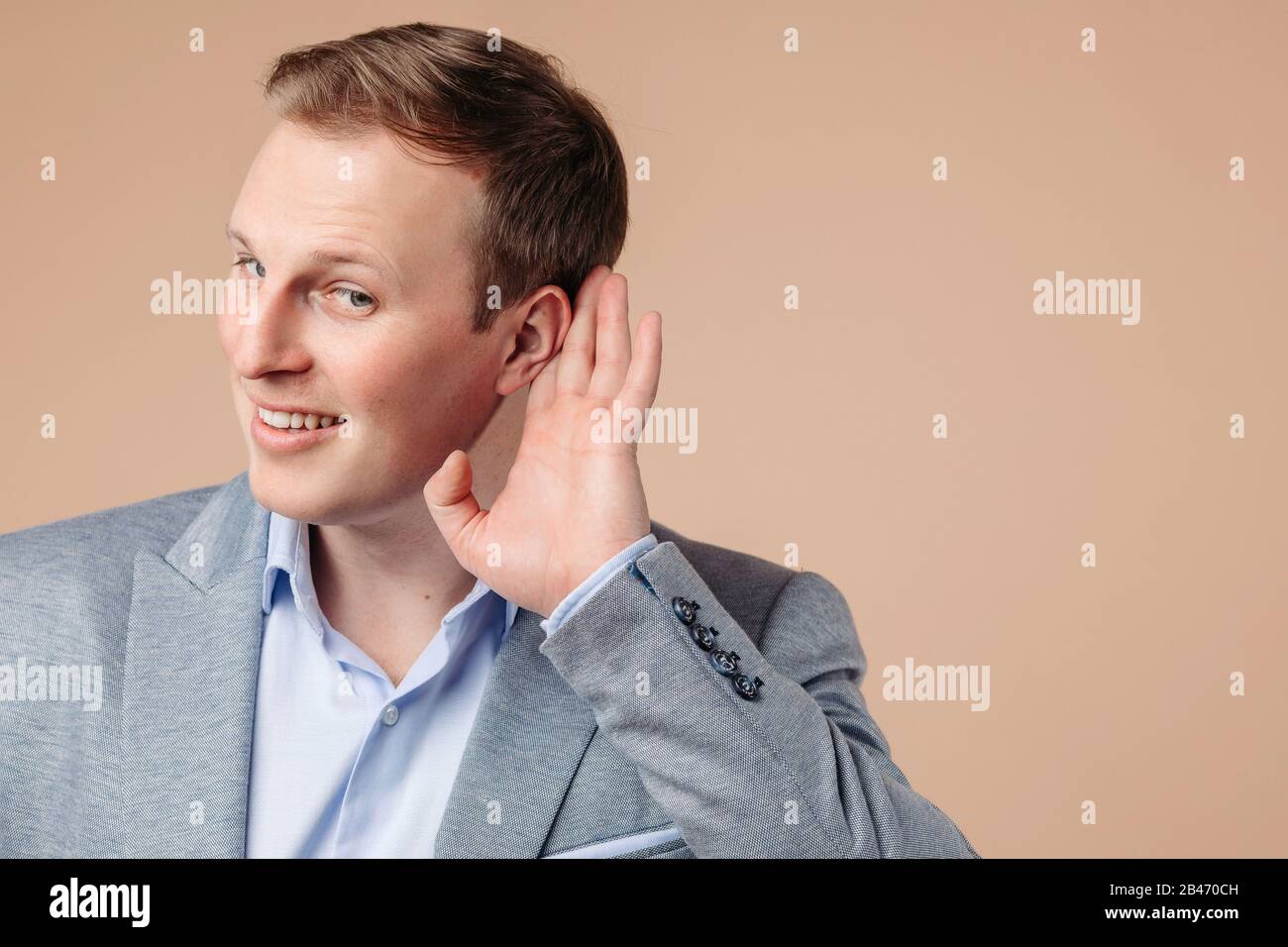 Ritratto di bell'uomo in grrey e blu ufficio vestito ascoltare per qualcosa e sorrisi Foto Stock