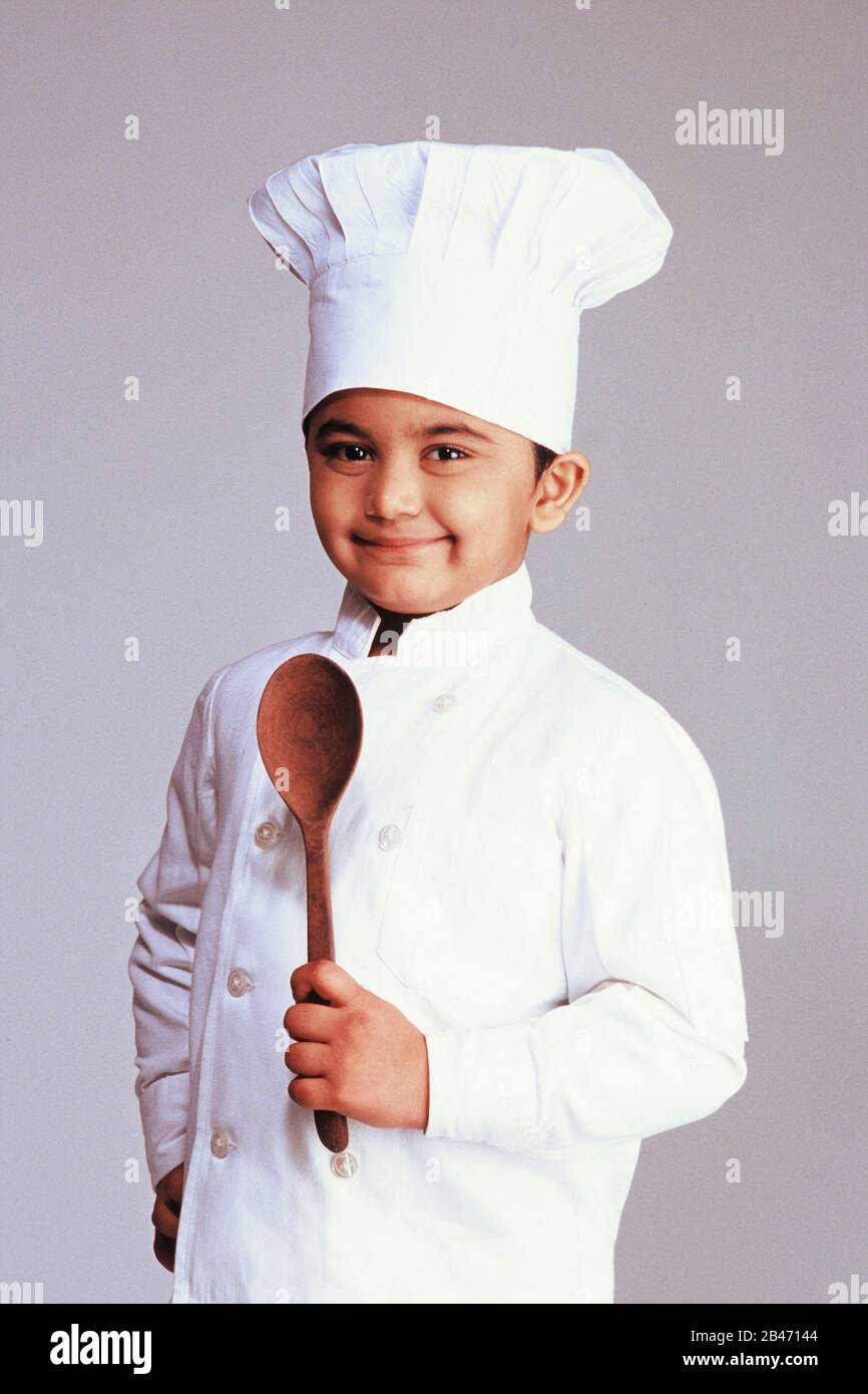 Ragazzo in abito elegante costume uniforme di chef che indossa giacca cappello bianco e cucchiaio da trasporto, MR n. Foto Stock