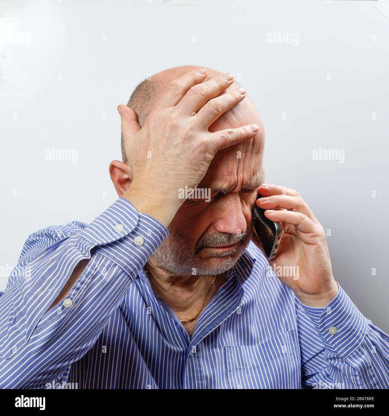 Un uomo di mezza età preoccupato mentre parla su un telefono cellulare Foto Stock