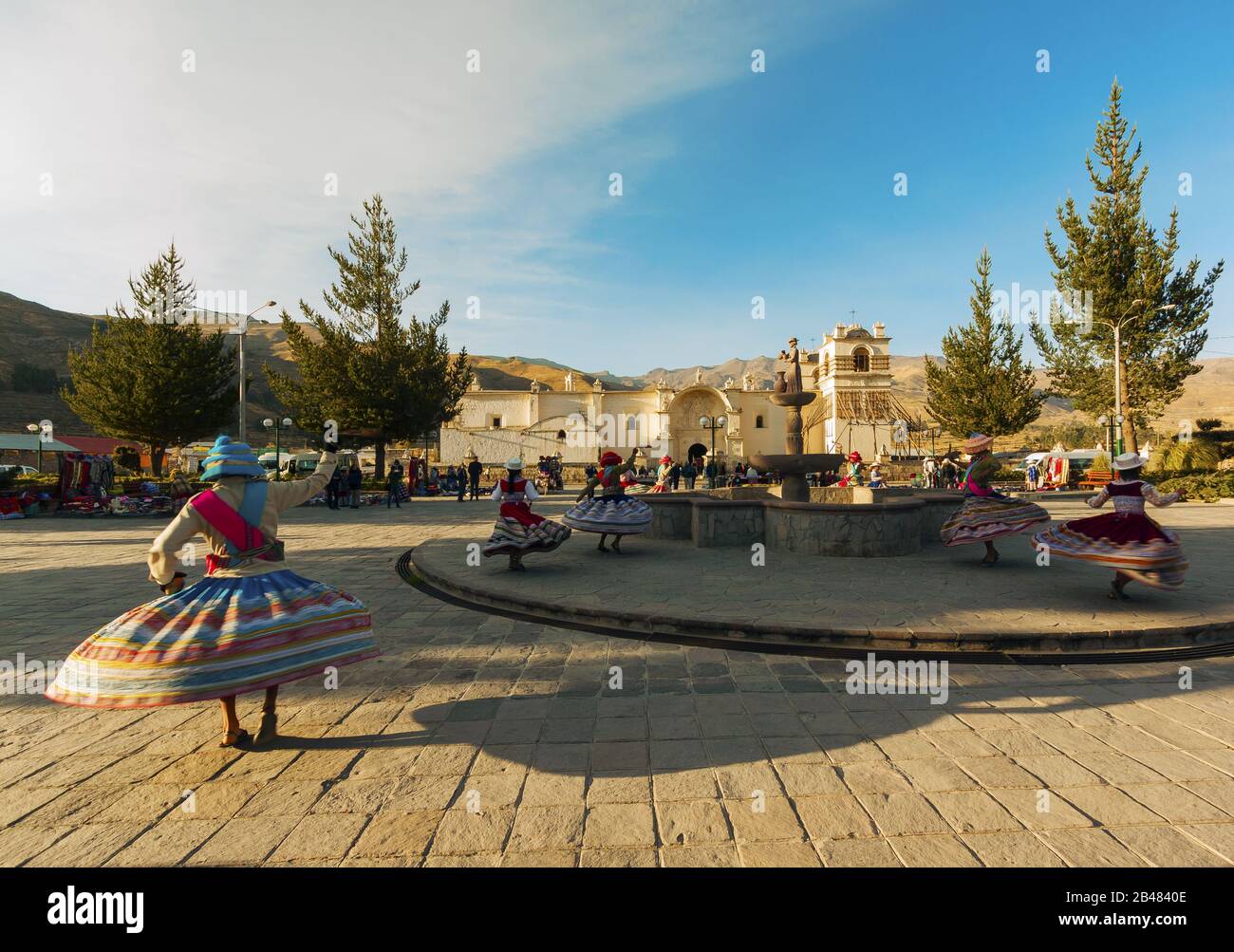 Chivay, ragazze joung che ballano in abiti tradizionali intorno a una fontana sulla piazza del villaggio, Perù Foto Stock